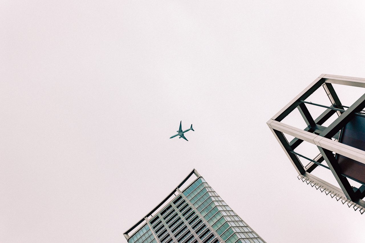 Flugzeug zwischen moderner Architektur und hellem Himmel